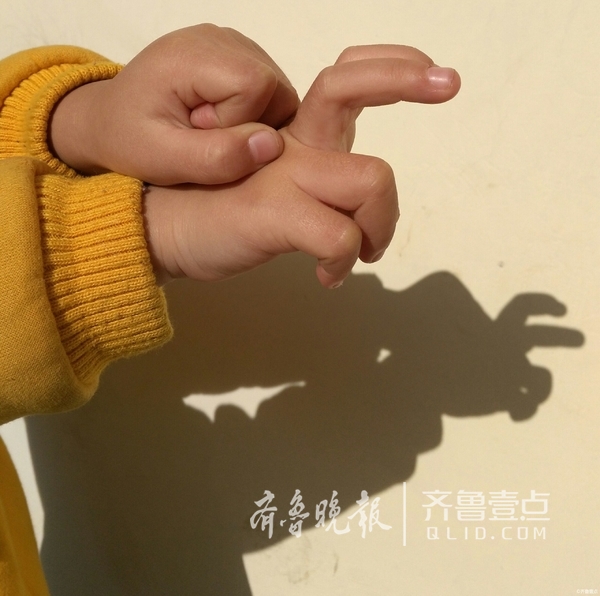 一组幼儿园小朋友在老师的带领下,沐浴阳光,用小手摆出不同的手影造型